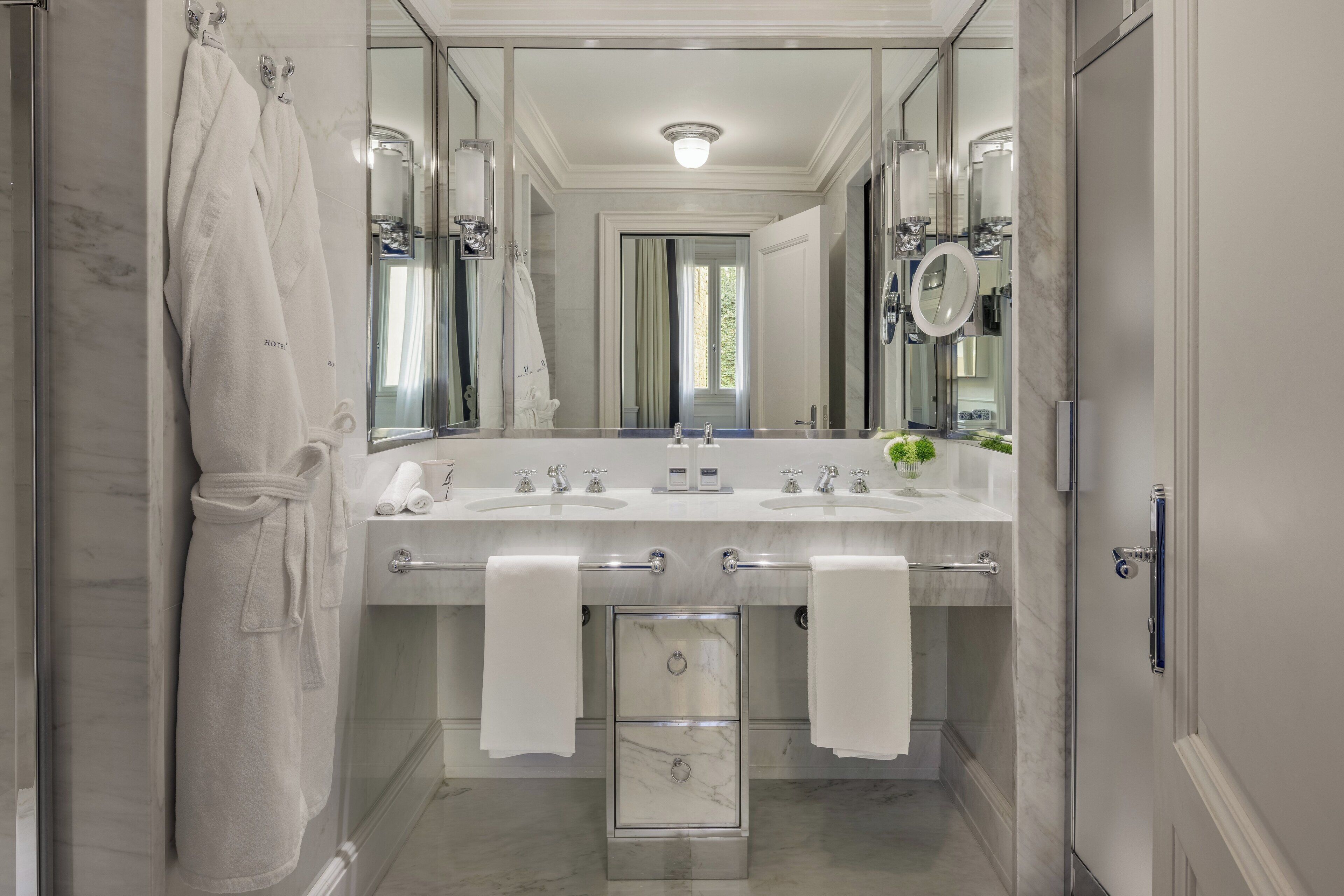 Un baño moderno con dos lavamanos, un espejo grande y una ducha a pie.