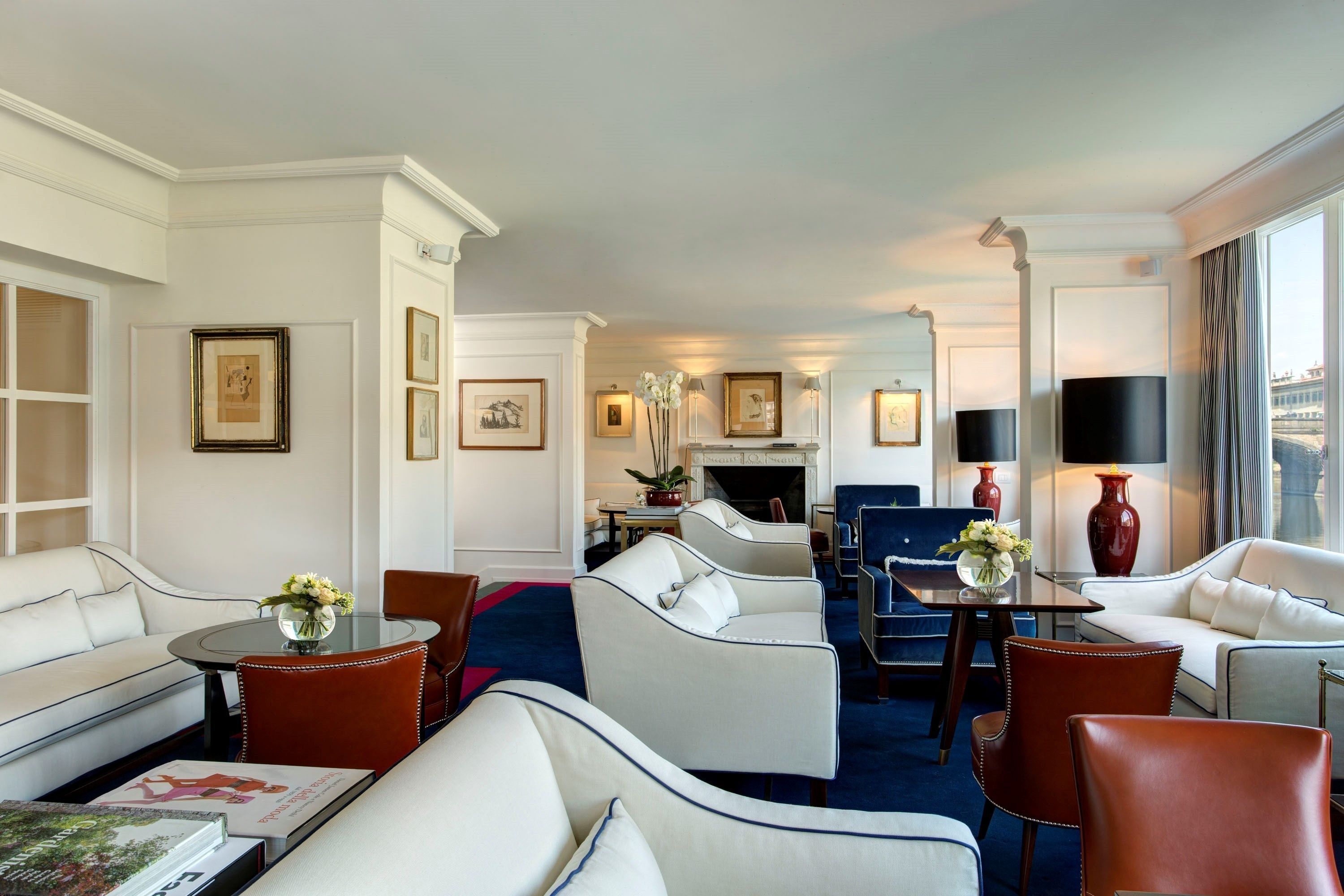 Une chambre d’hôtel dotée d’un espace salon comprenant un canapé, des fauteuils, une table basse et une cheminée.