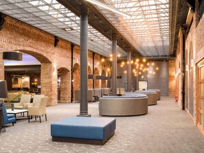 A spacious lobby with high ceilings, exposed brick walls, and modern seating areas. - Crowne Plaza Nottingham by IHG (Nottingham)