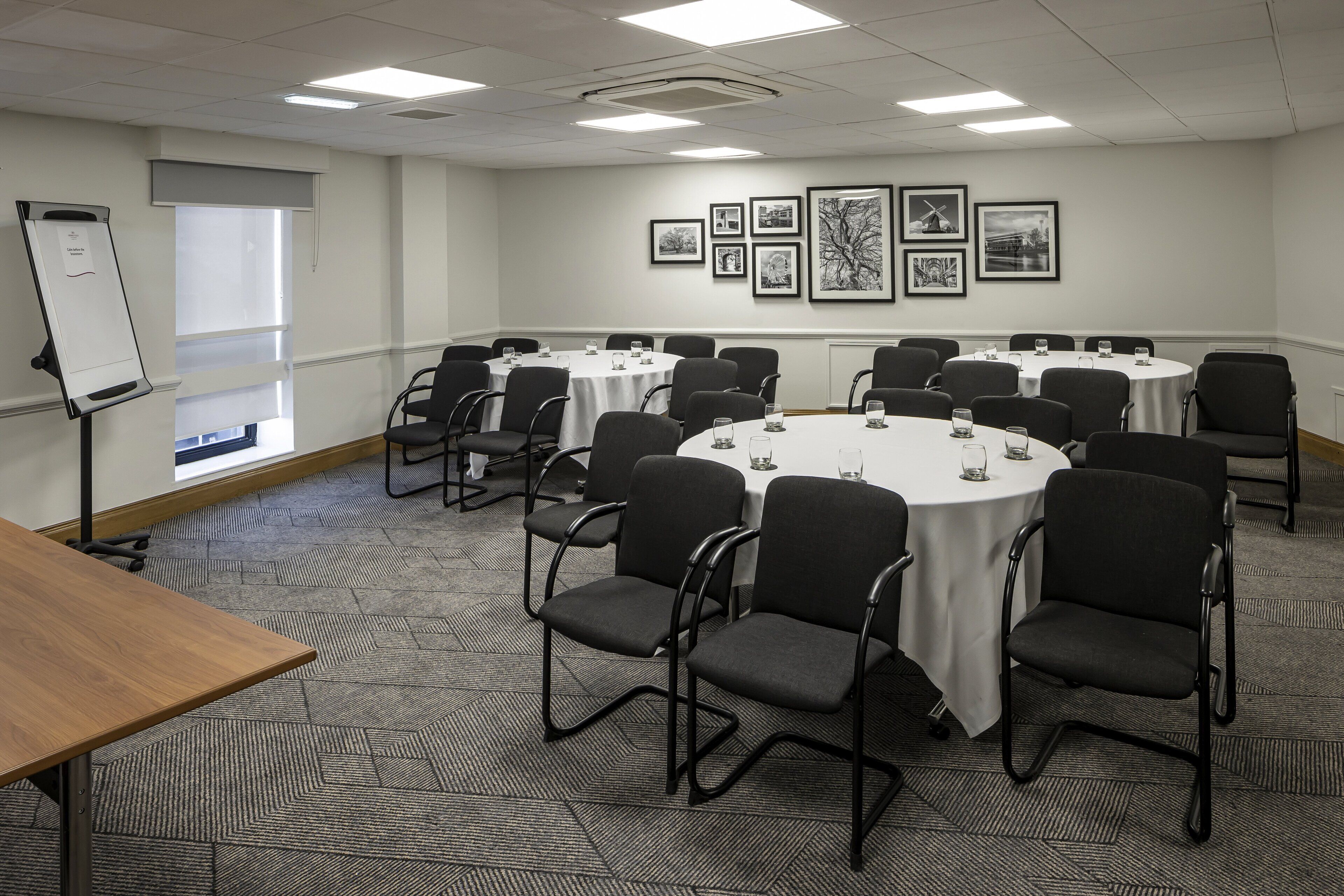 A conference room with round tables and chairs, a whiteboard, and framed pictures on the wall.