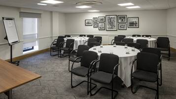A conference room with round tables and chairs, a whiteboard, and framed pictures on the wall.