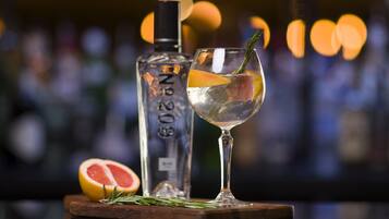 A bottle of No. 20 gin, a glass with a citrus slice and rosemary, and a half grapefruit on a wooden board.