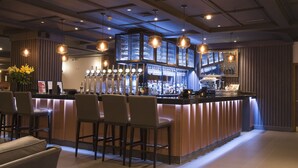 A bar area with a counter, bar stools, and a display of bottles. - Crowne Plaza Nottingham by IHG (Nottingham)