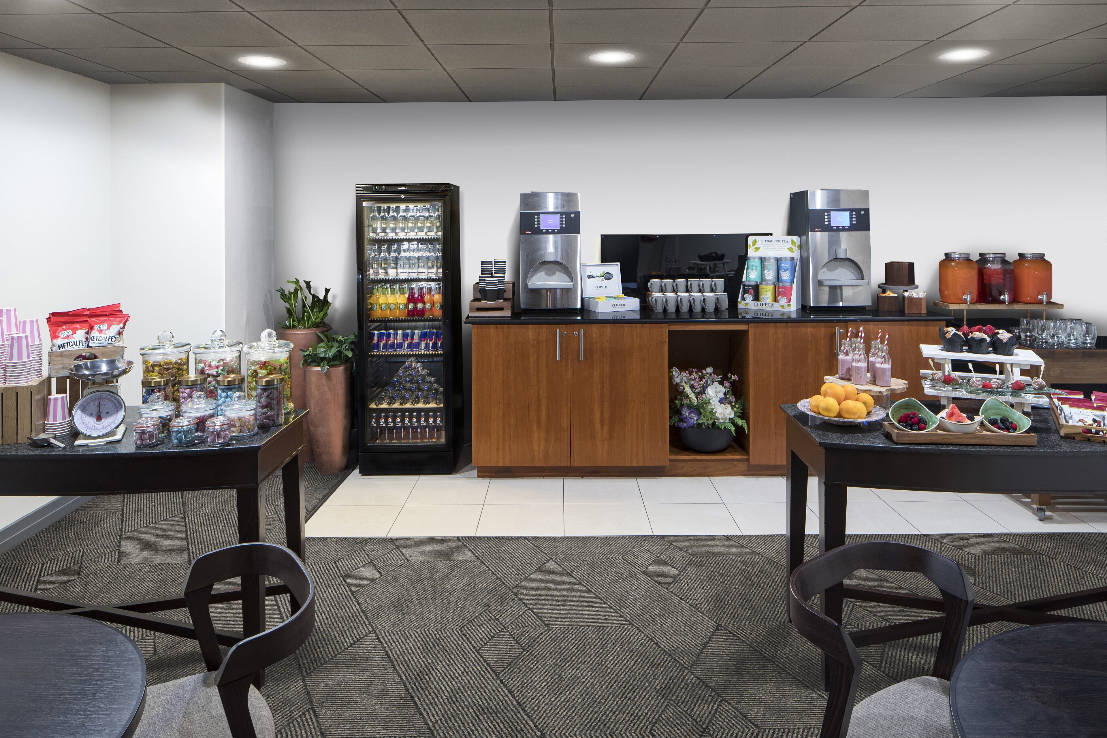 Un espace dédié au petit-déjeuner à l’hôtel, équipé d’un réfrigérateur, de machines à café et d’un présentoir de fruits.