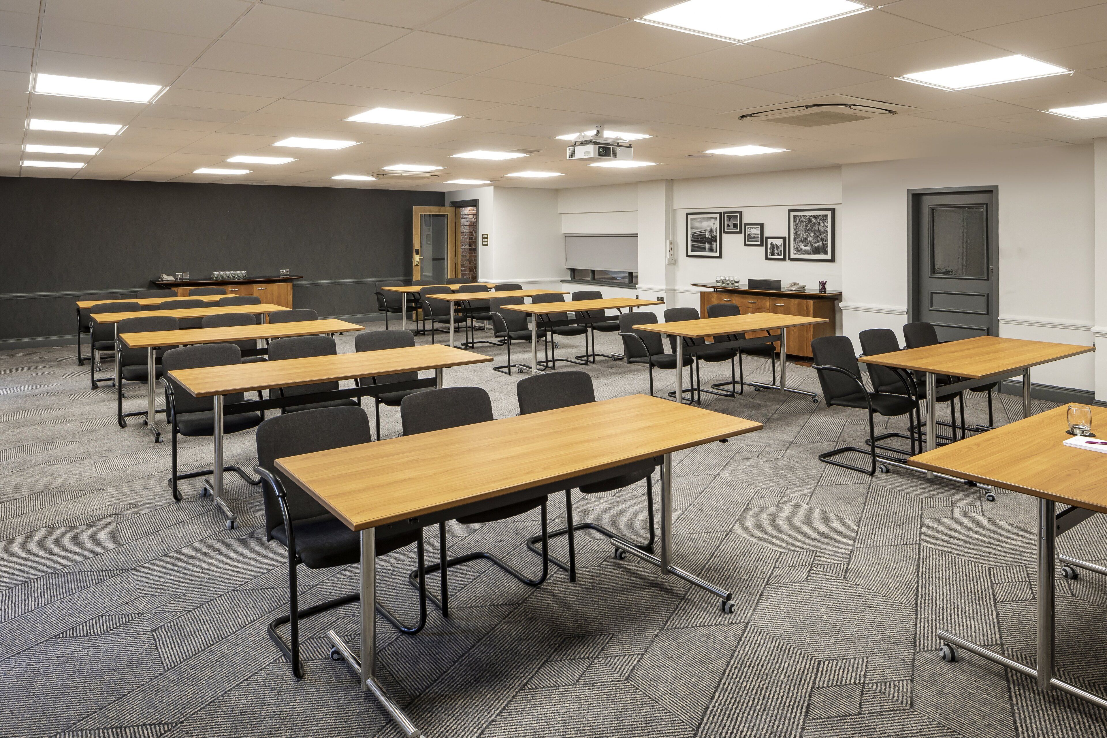 A classroom with rows of desks and chairs, a projector, and a whiteboard.