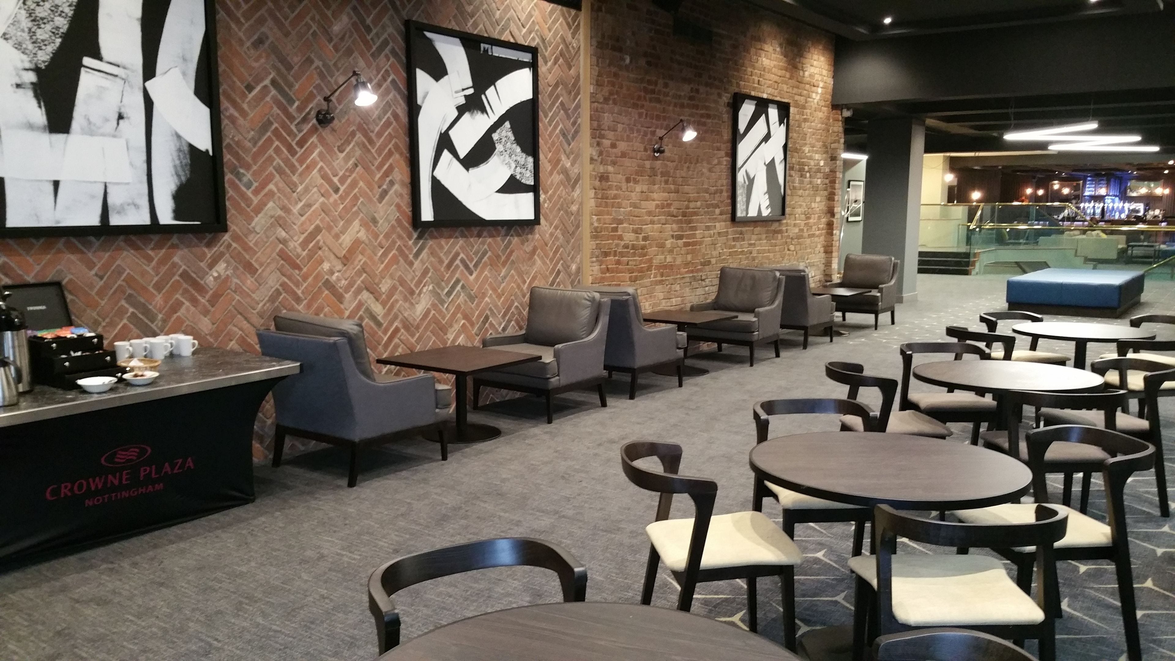 A modern cafe with brick walls, abstract art, and a variety of seating options including tables and chairs.