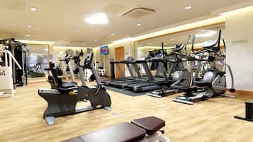 A gym with various exercise equipment including treadmills, elliptical machines, and stationary bikes.