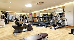Ein Fitnessstudio mit unterschiedlichen Trainingsgeräten, darunter Laufbänder, Crosstrainer und Ergometer.