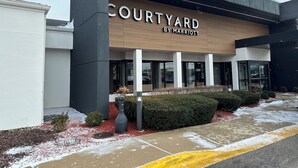 A Courtyard by Marriott hotel entrance with a modern design, large glass windows, and a snow-covered ground. - Courtyard by Marriott Chicago Glenview/Northbrook (Northbrook)