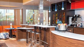 A modern kitchen with a central island, bar stools, and a coffee machine.