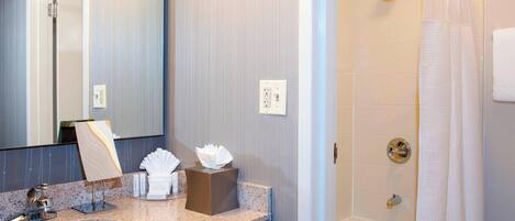 A bathroom with a sink, mirror, towel rack, and shower.