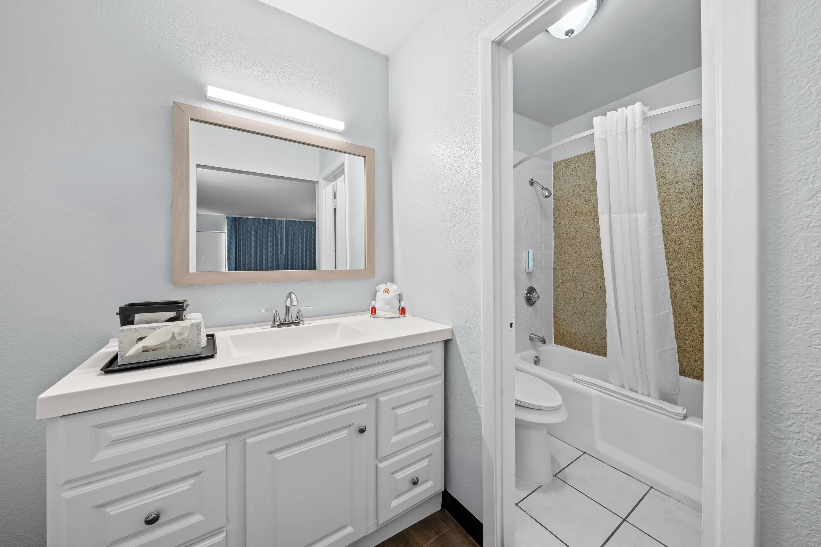 A modern bathroom with a white vanity, a mirror, and a shower area.
