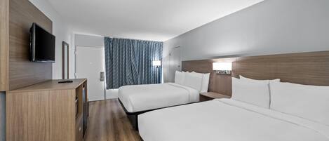 Een hotelkamer met twee bedden, een televisie, een bureau en een raam met gordijnen.