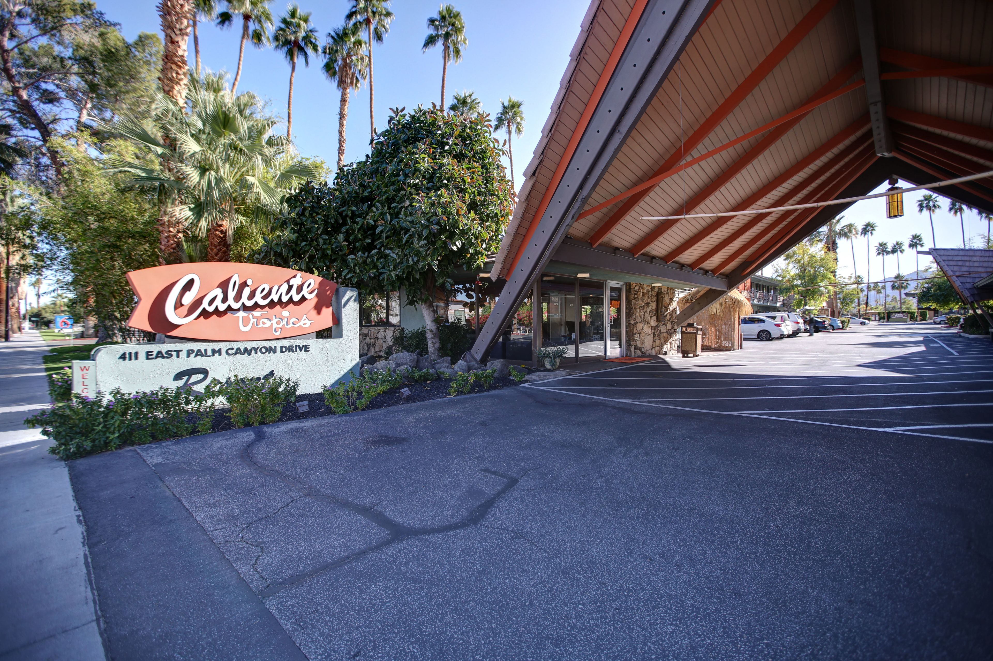A hotel entrance with a sign reading "Caliente Topics 411 East Palm Canyon Drive."