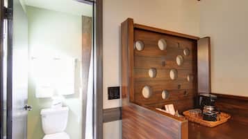 A bathroom with a wooden vanity, a coffee maker, and a tray with toiletries.