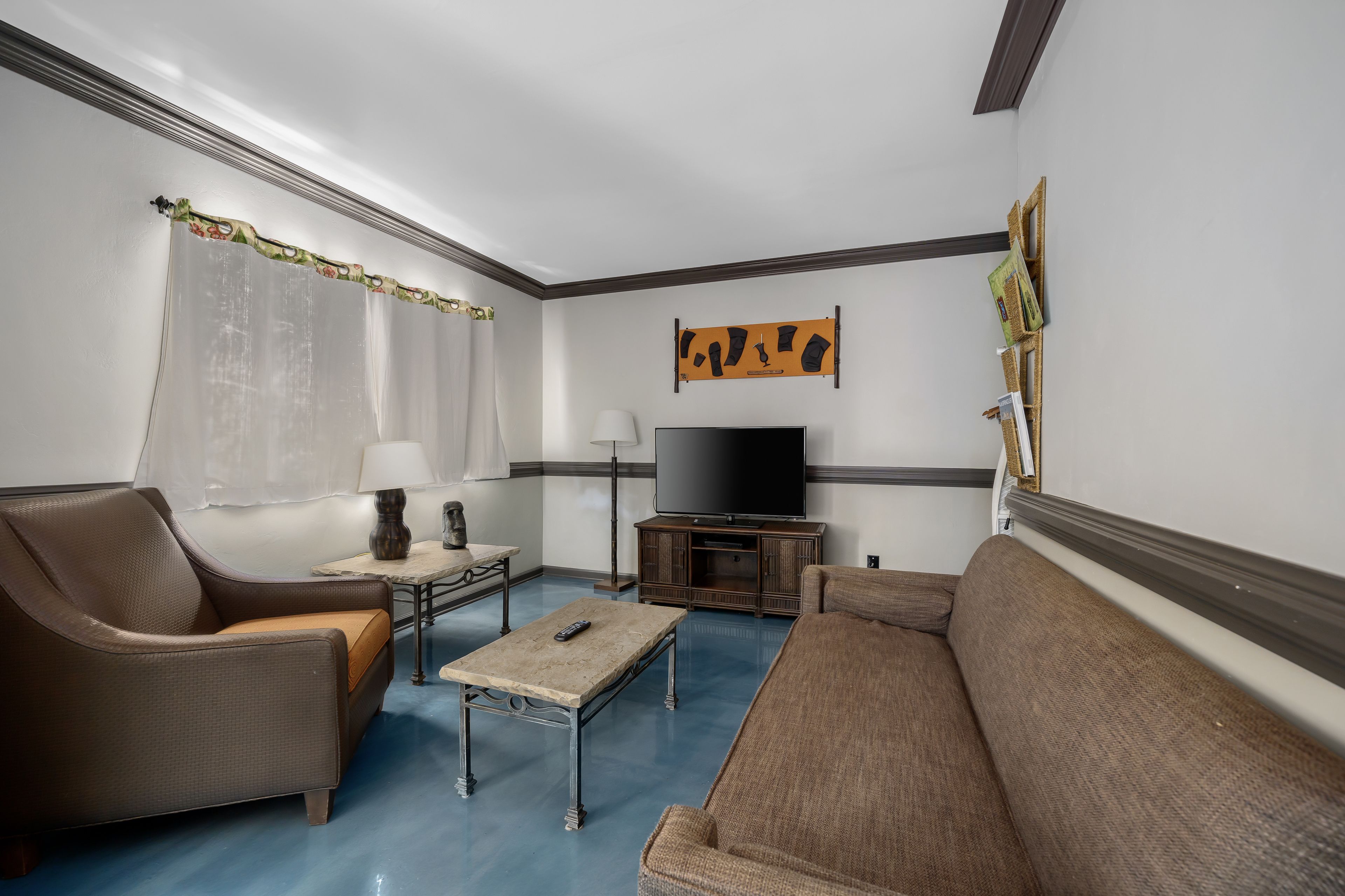 A living room with a sofa, armchair, coffee table, TV, and decorative items.