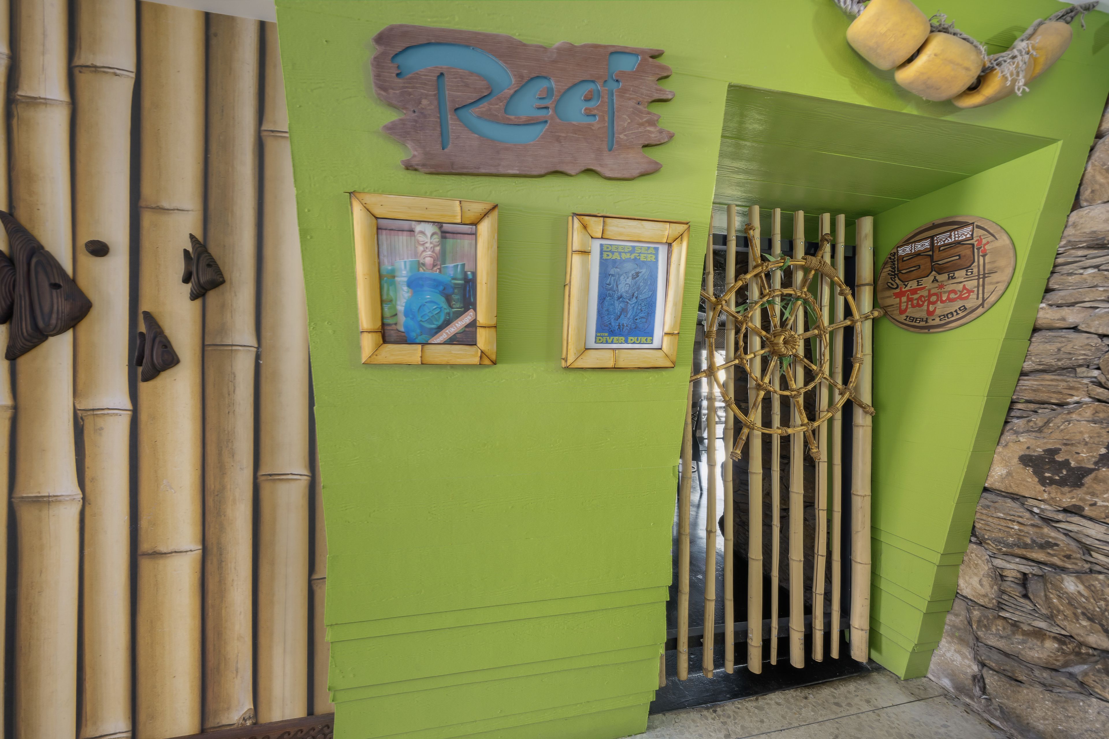 Un muro verde con un'insegna 'Reef', quadri incorniciati, una ruota decorativa e una targa che celebra '55 anni'.