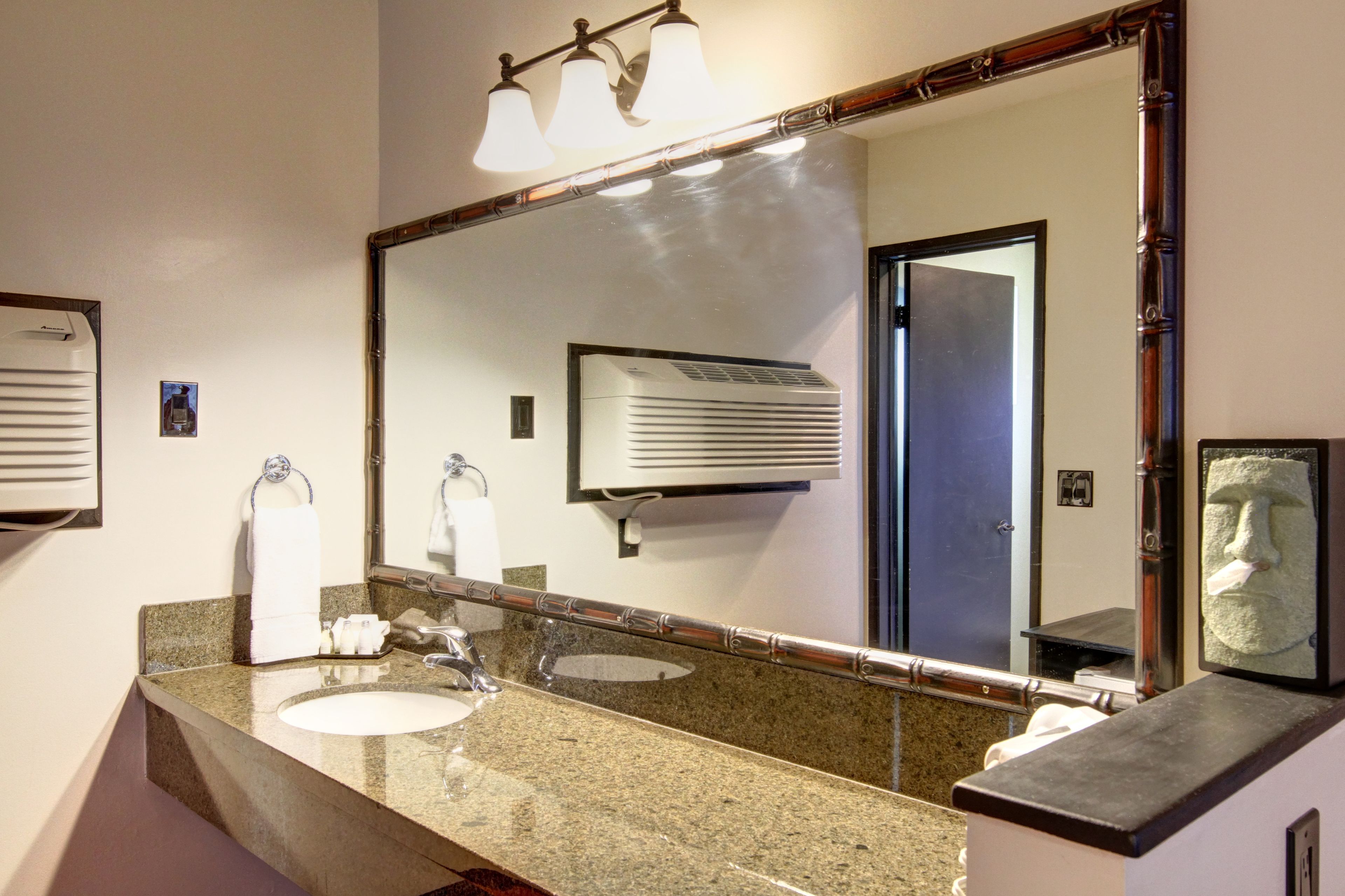 Une salle de bain avec deux lavabos, un grand miroir et un porte-serviettes.