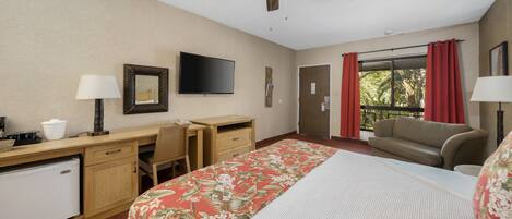 A hotel room with a bed, desk, chair, television, and a window with curtains.
