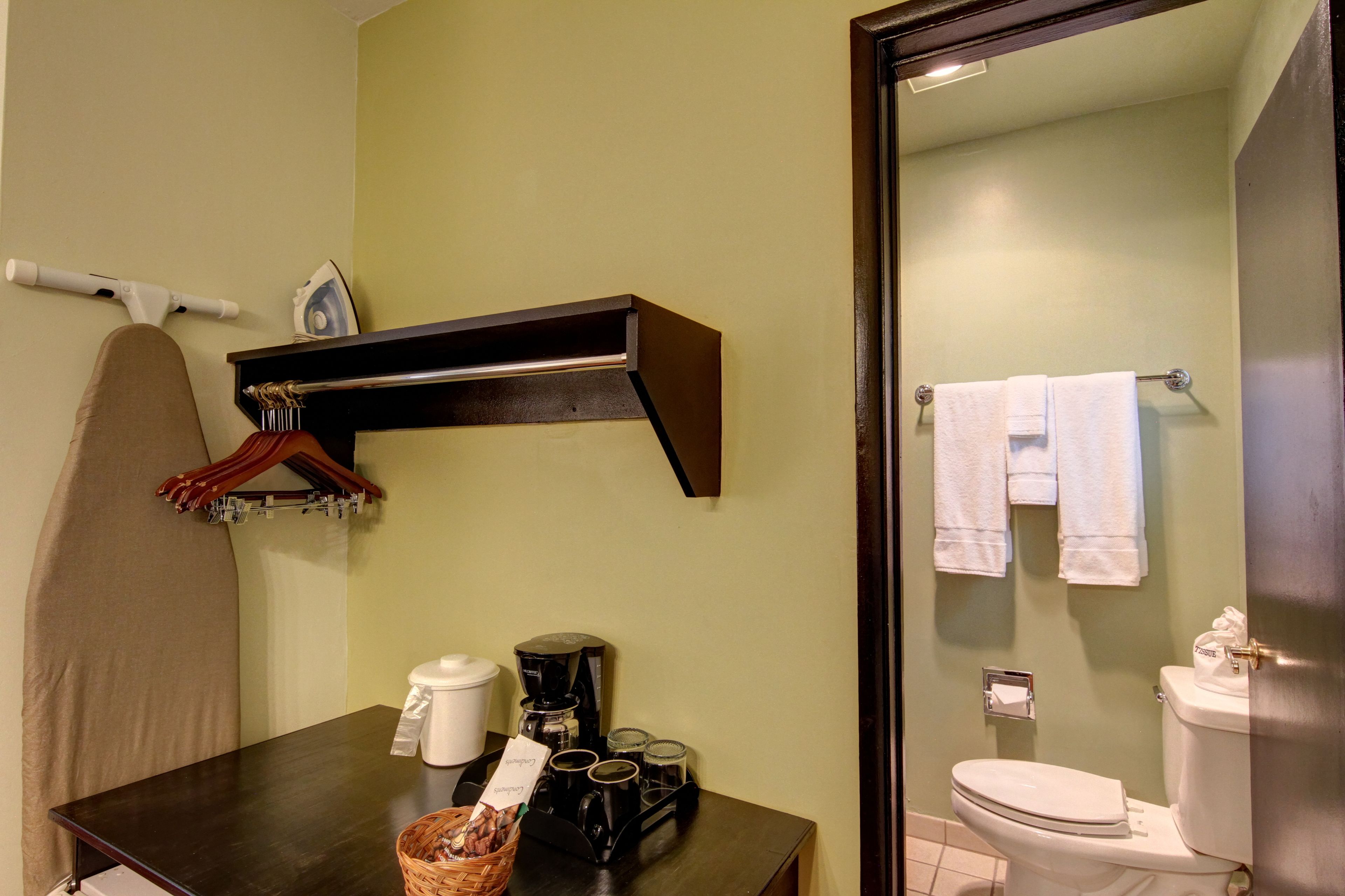 A bathroom with a toilet, a sink, and a shower area. There is a towel rack with towels and a shower curtain.