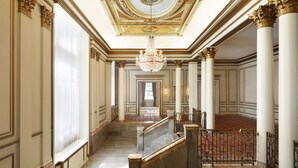 Un amplio pasillo con suelos de mármol, columnas ornamentadas y un candelabro.