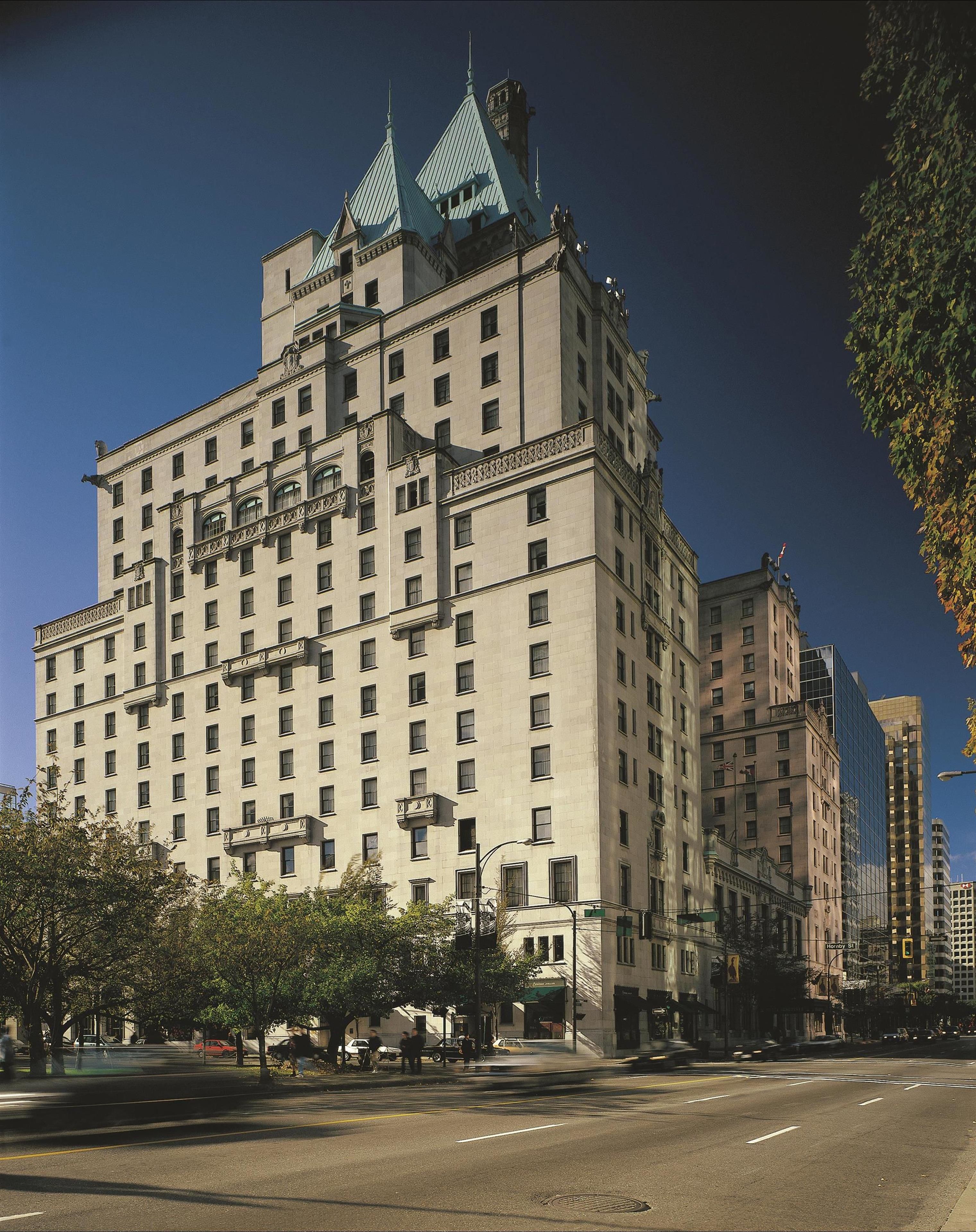 A large, historic hotel with a prominent corner location, multiple floors, and a distinctive architectural style featuring a central tower with a green roof.