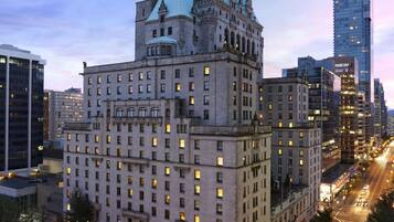 A large, historic building with a prominent tower and multiple floors, surrounded by modern high-rise buildings.