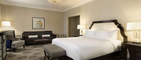 Une chambre d’hôtel avec un grand lit, un canapé, un bureau et un lustre.
