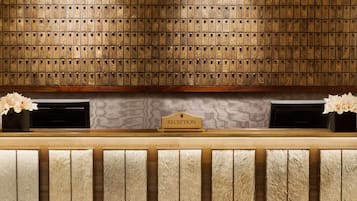 A reception area with a wooden wall displaying numerous letters, a reception desk, and two flower arrangements.