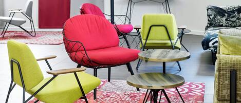 A modern living room with vibrant chairs, a small round table, and a sofa.