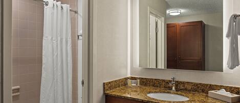 A bathroom with a shower, a sink, and a mirror.
