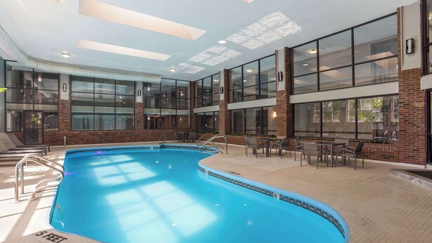 An indoor swimming pool with clear glass walls, a tiled floor, and a 5 feet depth marking.