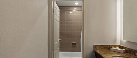 Een badkamer met een douche, een wastafel en een spiegel.