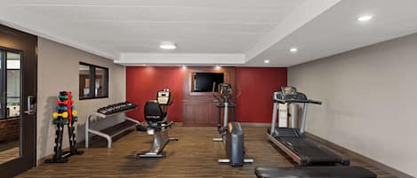 A gym with cardio equipment, weight machines, and a bench.