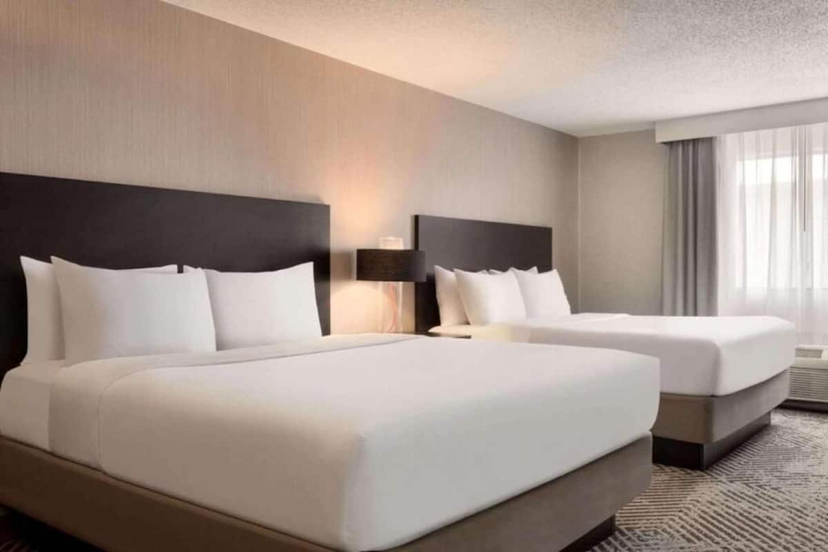 Ett hotellrum med två sängar, ett stort fönster och en modern design.