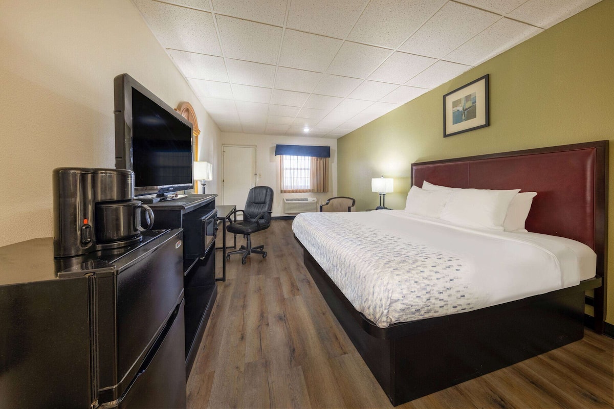 Habitación de hotel con cama, escritorio, silla, televisor y cafetera.