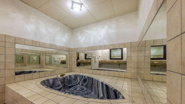 A modern bathroom with a central hot tub, large mirrors, and tiled walls. - Baymont by Wyndham El Dorado (El Dorado)