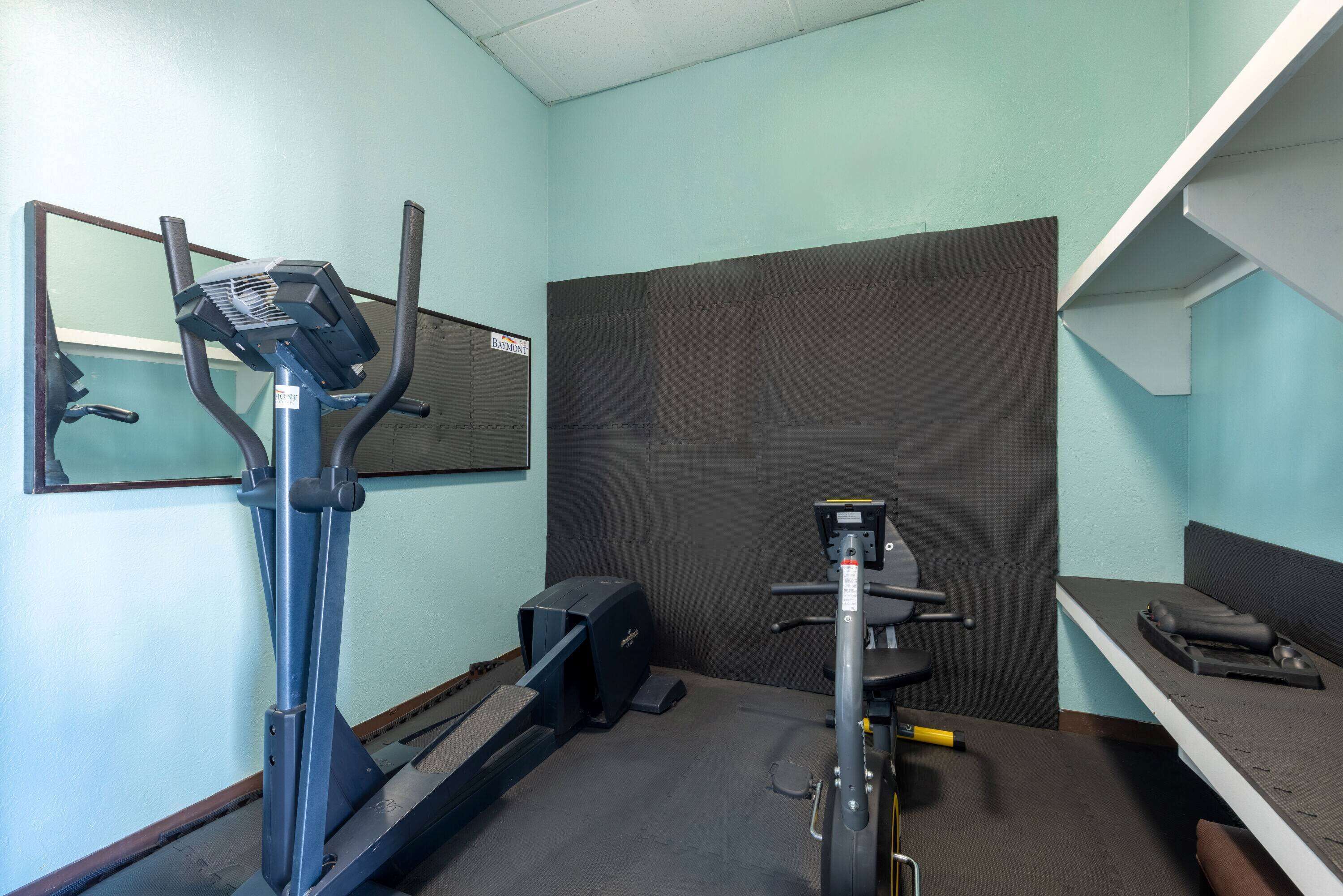 A small gym with a treadmill, stationary bike, and a bench.