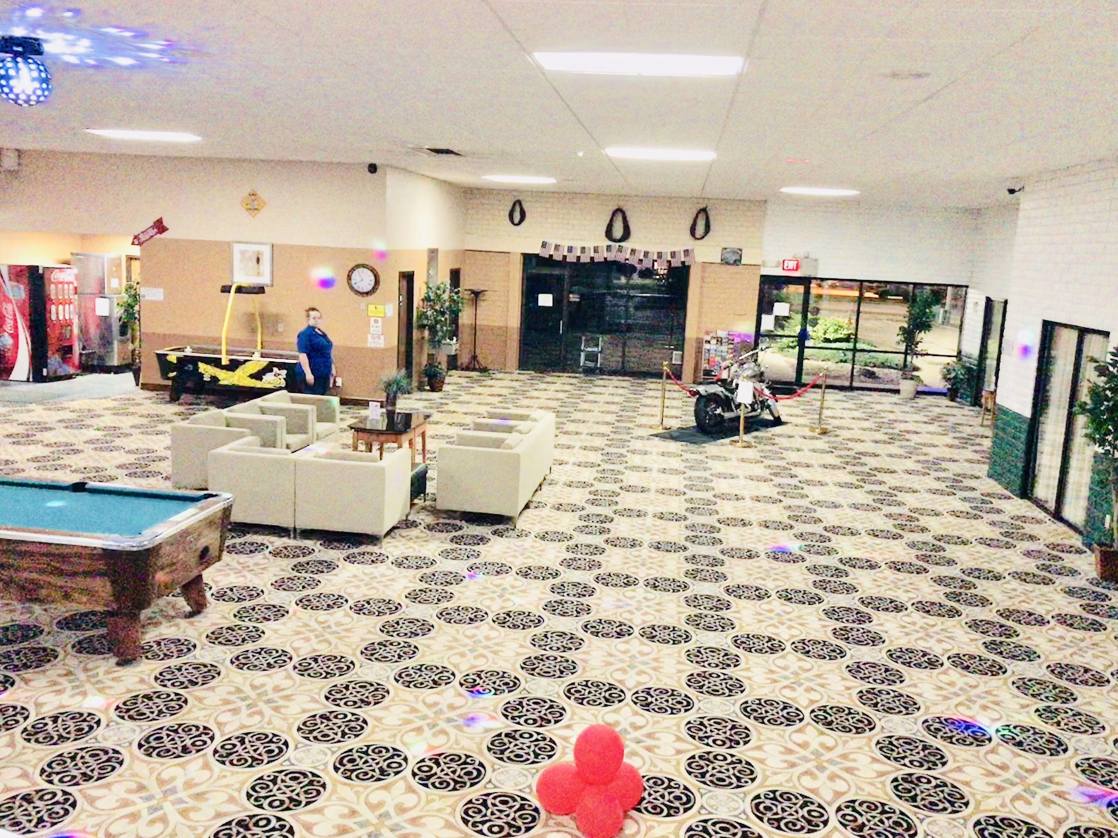 Eine geräumige Lobby mit Billardtisch, Sitzgelegenheit und einem Motorrad.