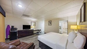 A hotel room with a large bed, a desk, a television, and a leather sofa. - Baymont by Wyndham El Dorado (El Dorado)