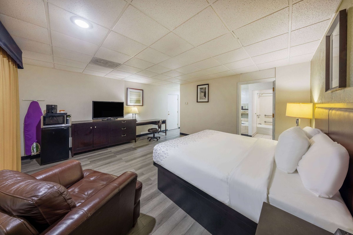 Una habitación de hotel con una cama grande, un escritorio, un televisor y un sofá de cuero.
