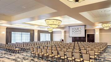 A conference room with rows of chairs, a projector screen, and a podium.