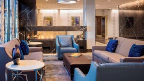 A modern lobby with a fireplace, seating area, and a reception desk. - Four Points By Sheraton Norwood (Norwood)
