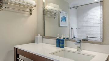 A modern bathroom with a large mirror, white sink, and two bottles of ACTIV body wash.