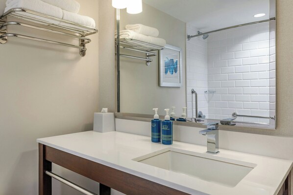 Un baño moderno con un espejo grande, un lavabo blanco y dos botellas de crema corporal ACTIV.