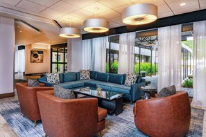 A modern lounge area with a sectional sofa, armchairs, and a coffee table. - Four Points By Sheraton Norwood (Norwood)