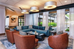Un espacio lounge moderno con un sofá seccional, sillones y una mesa de centro.
