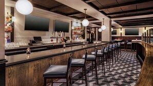 A bar area with a long counter, multiple bar stools, and a patterned floor. - Four Points By Sheraton Norwood (Norwood)