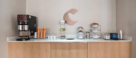 Un espace café moderne, équipé d’une machine à café, de tasses et de divers produits alimentaires.