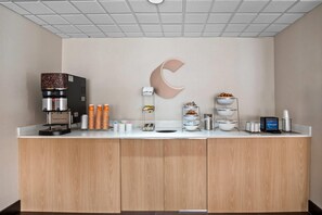 A modern coffee station with a coffee machine, cups, and various food items.